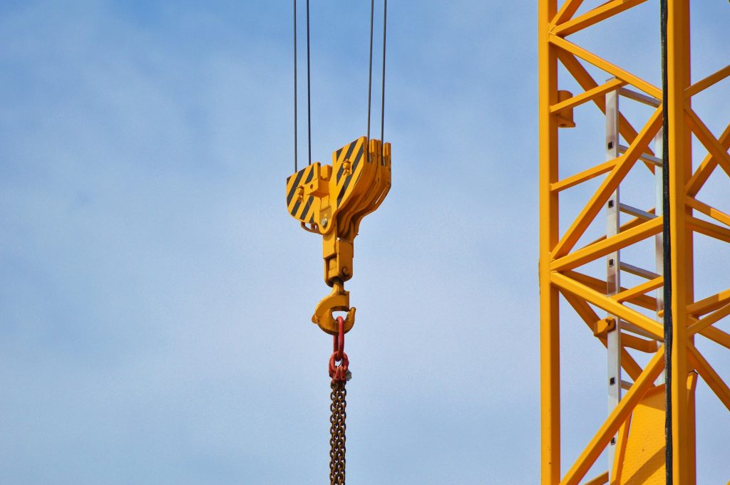 Close-up of a yellow crane arm against a clear blue sky, showcasing industrial equipment.