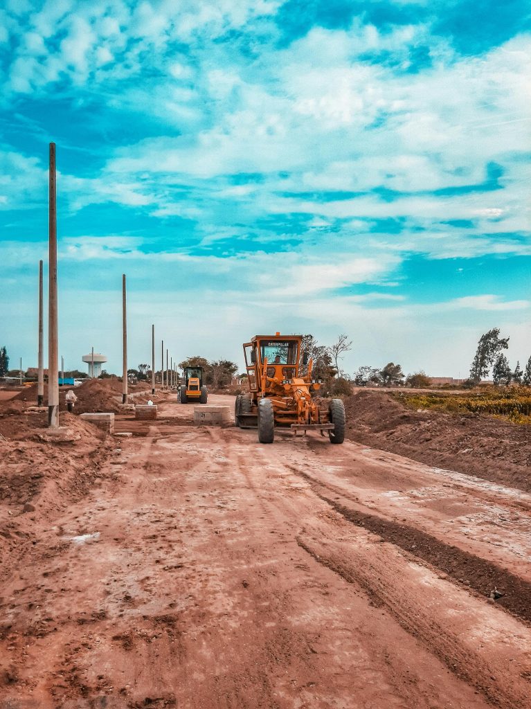 Yellow bulldozer working on a dirt road under a blue sky, ideal for construction themes.